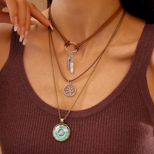 Dettaglio della collana boho a strati con ciondoli albero della vita e piuma su modella