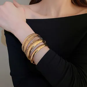 Ensemble de huit bracelets dorés aux finitions polies et texturées portés par un mannequin