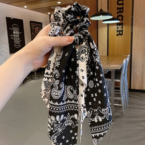 Elegant black and white paisley silk hair scrunchie with long ribbons held by hand