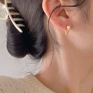 Close-up of elegant gold heart-shaped hoop earrings worn by a model in warm light