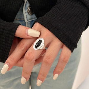 Close-up of a silver ring featuring a smooth oval black agate stone on a hand