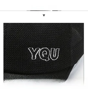 Gros plan sur la broderie blanche YQU sur une casquette en maille noire respirante