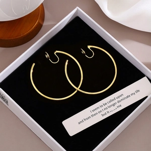 Detailed view of polished gold clip-on hoop earrings in a white jewelry box with silk
