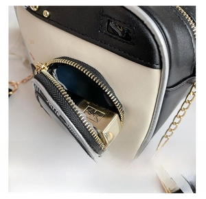Detail view of the front zipper pocket on a color-block bag with a lipstick inside