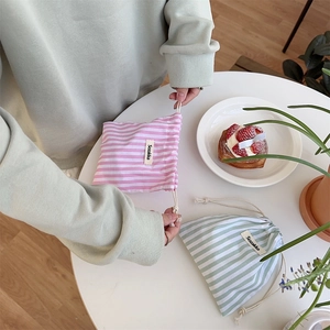 Close-up of pink and green striped cotton drawstring pouches on a white table