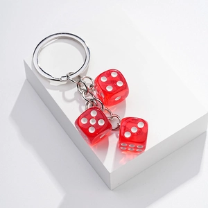 Detailed view of three red transparent dice attached to a metal keychain on a white stand
