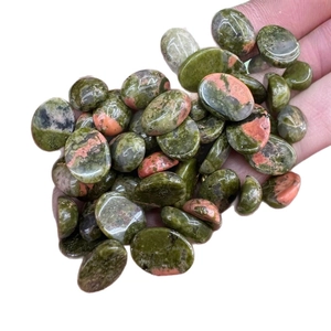 Polished oval unakite stones held in hand for handmade DIY jewelry making projects