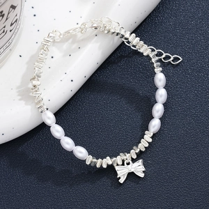 Detail of silver irregular beads and faux pearl bracelet with a cute bow charm