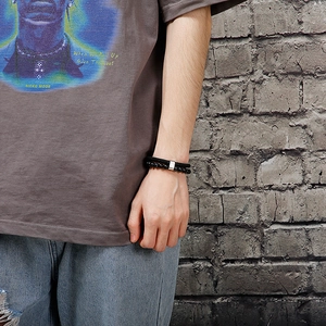 Close-up of black beaded bracelet and braided rope wrap on male model's wrist