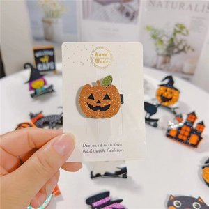 Dettaglio di fermaglio per capelli a zucca arancione glitterata con foglie verdi su carta