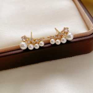 Macro shot of 18k gold-plated pearl earrings with sparkling cubic zirconia on silk