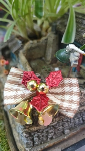 Close-up of linen bow with red glitter leaves and golden bells for Christmas tree