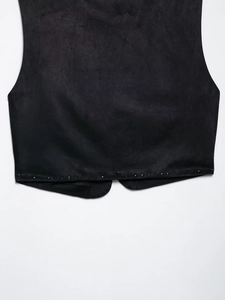 Dettaglio dell'orlo del gilet in pelle scamosciata nera con piccole borchie e tessuto morbido