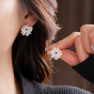 Détail de boucles d'oreilles flocon argentées avec perles et zircons sur modèle