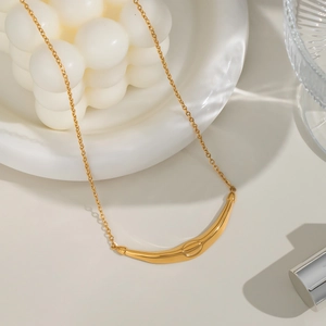 French vintage gold curved bar necklace displayed on a white ceramic plate decoration