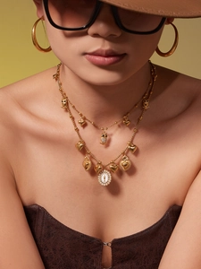 Detail of gold layered heart necklace and oversized hoop earrings on a fashion model