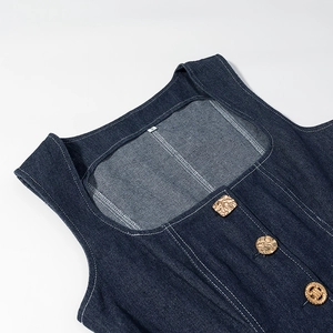 Détail de gilet en denim bleu foncé avec coutures blanches et boutons en métal doré