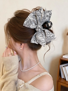 Macro view of a black and white paisley bow hair claw clip showing fabric texture