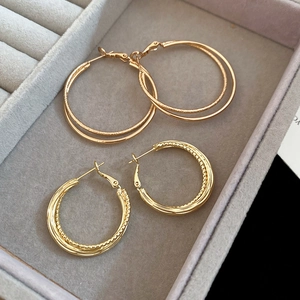 Detail of gold circular hoop earrings with woven and textured patterns in a jewelry box