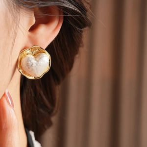 Vue détaillée de la boucle d'oreille cœur en perle plaquée or 16K portée par le mannequin