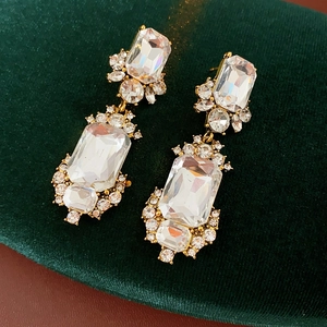 Close-up of vintage gold square earrings with emerald-cut crystals on green velvet