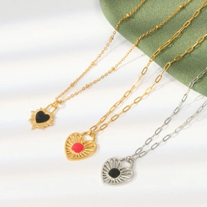 Vintage gold and silver heart necklaces with enamel inlay on textured green fabric