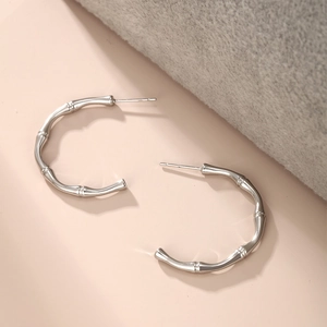 Detailed macro shot of silver bamboo-style C-shaped hoop earrings for women