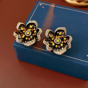 Macro shot of vintage floral stud earrings with colorful crystals on a jewelry box