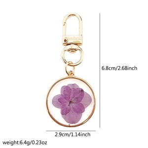 Detailed view of handmade key ring with pressed purple flowers and size specifications
