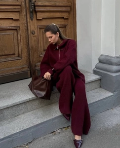 Detail of burgundy knitted texture on half-zip sweater and high-waist trousers