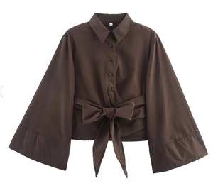 Détail d'une chemise en popeline marron foncé avec poignets larges et noeud à la taille