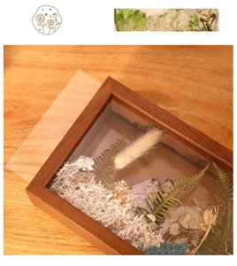 Macro detail of wooden shadow box frame with preserved dried flowers and acrylic panel