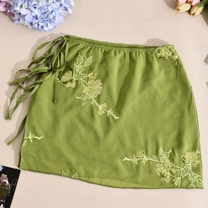 Close-up of grass green mini dress with floral sequin embroidery and side tie detail
