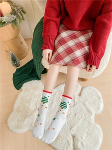 Détail de chaussettes de Noël en molleton corail avec motifs sapins sur un tapis douillet