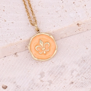 Detailed close-up of a gold fleur-de-lis pendant with orange enamel on a fine chain