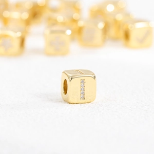 Macro view of a 18k gold plated cube pendant with zircon inlaid letter I detail