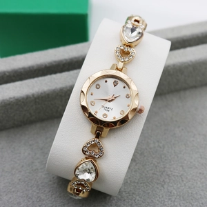 Close-up of gold quartz watch with sparkling rhinestones and heart-shaped chain bracelet