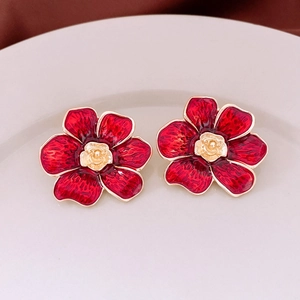 Detail of vintage red enamel flower earrings with gold rose center and petal texture