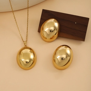 Close-up of golden oval pendant necklace and earrings with a polished metallic finish