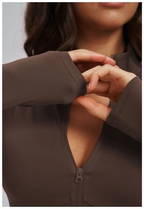 Detail of dark brown yoga jacket showing half-zip neckline and smooth high-stretch fabric