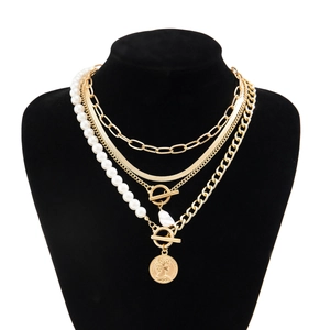 Detail of layered gold necklace featuring baroque pearl and Elizabeth coin pendant