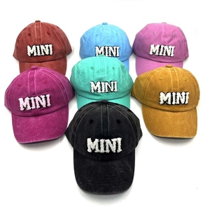 Flat lay of multiple washed cotton baseball caps with MINI embroidery in seven vibrant colors