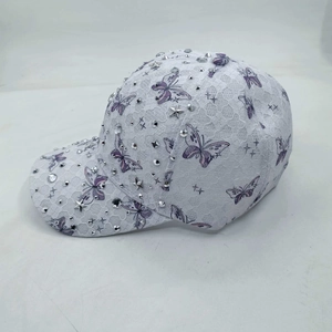 Detail of white lace baseball cap with purple butterfly prints and sparkling rhinestones