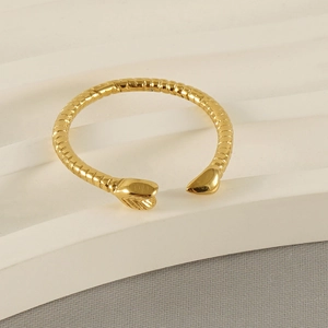 Detail of golden snake ring with scale texture on a white display stand