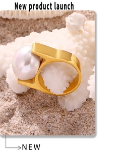 Chunky gold pearl ring displayed on white coral over soft sand for a beach vibe
