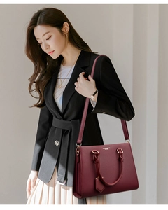 Burgundy genuine leather handbag worn on shoulder by model in elegant black blazer suit