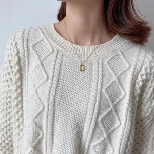 Minimalist irregular gold necklace detail worn by model with textured knit sweater