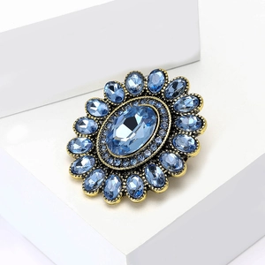 Dettaglio di spilla in bronzo vintage con grande cristallo blu e strass luminosi