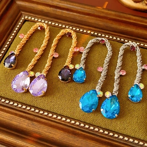Detailed macro view of vintage woven metal drop earrings with colorful crystals