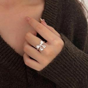 Minimalist S925 sterling silver bow knot ring worn on hand with a cozy knitted sweater